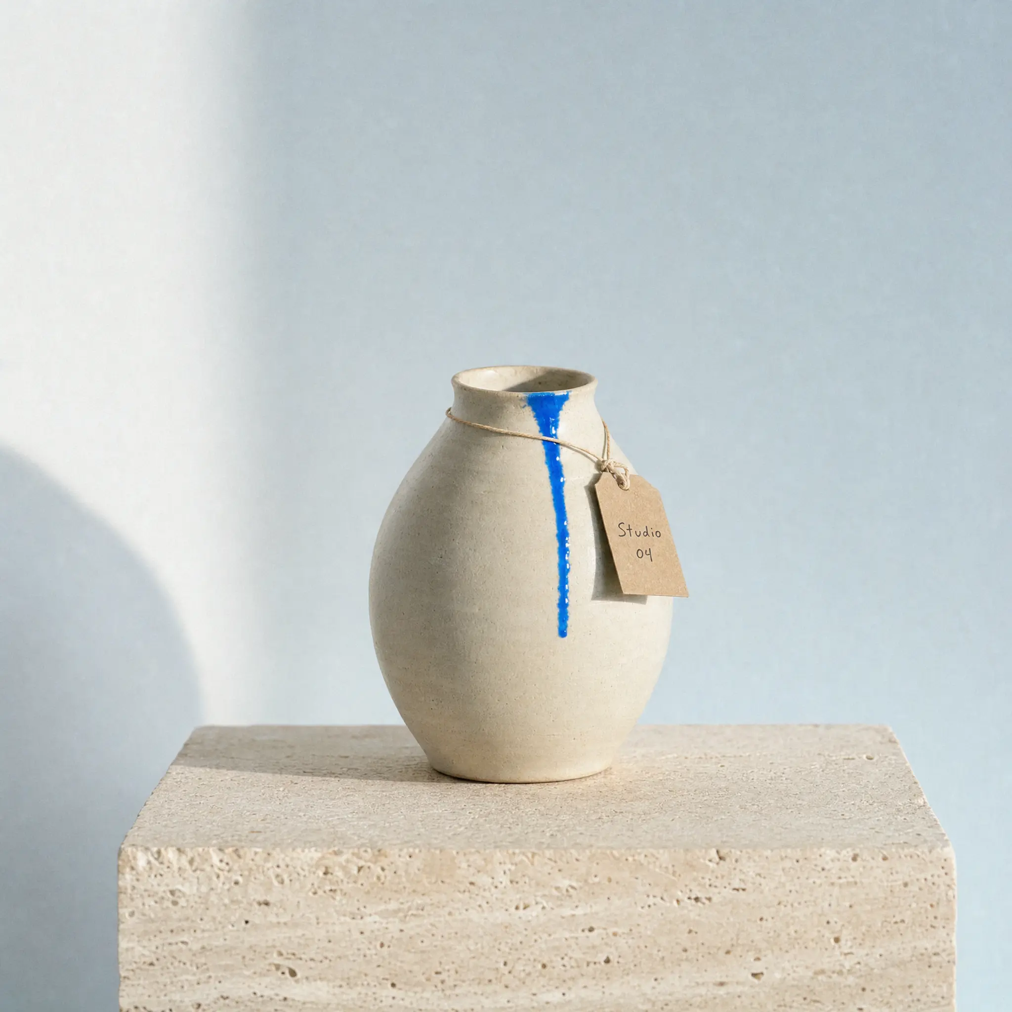 The vase on travertine with a tag that reads Studio 04