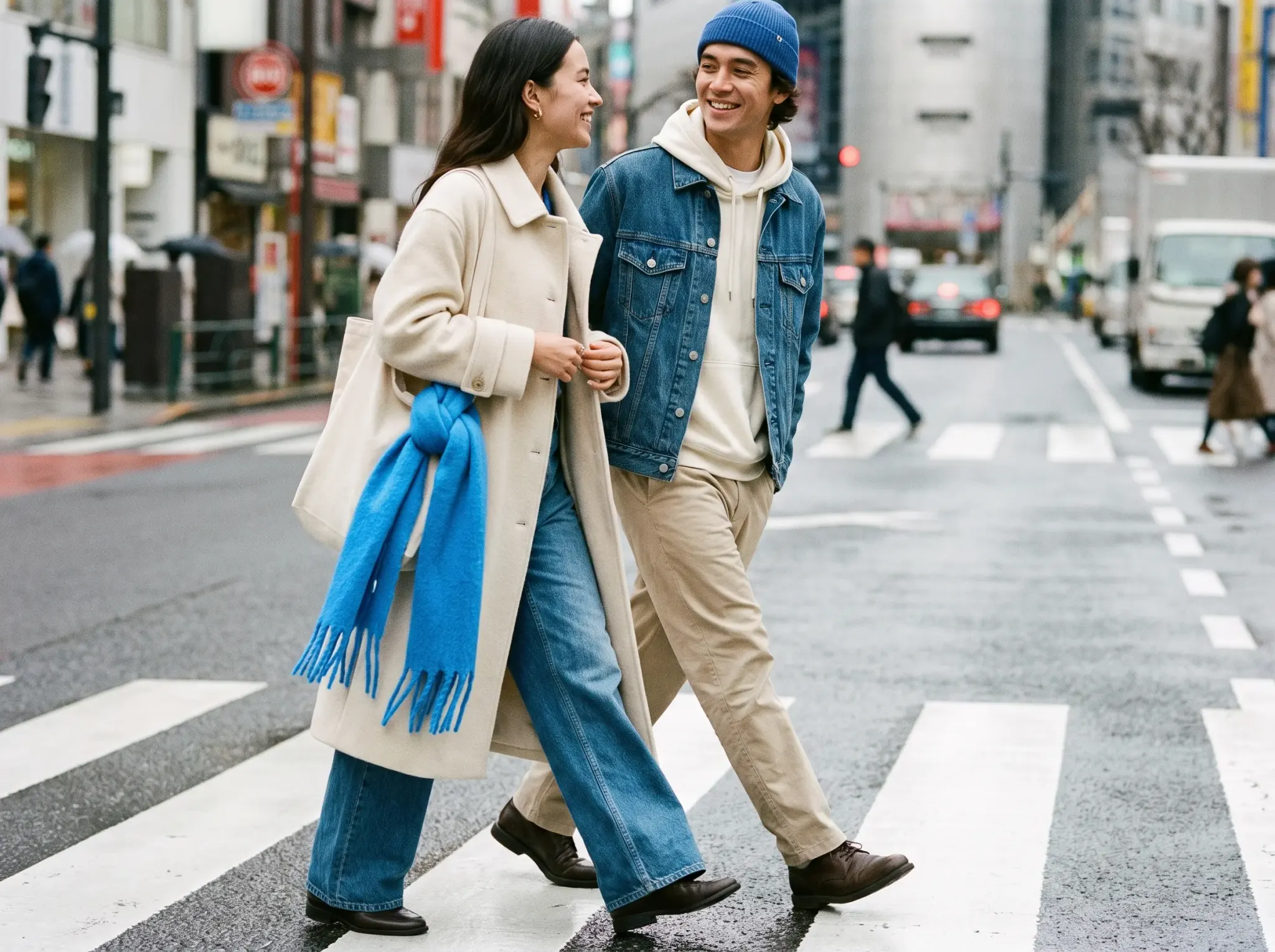 A street-style shot of two friends in denim and cream crossing a Tokyo crosswalk