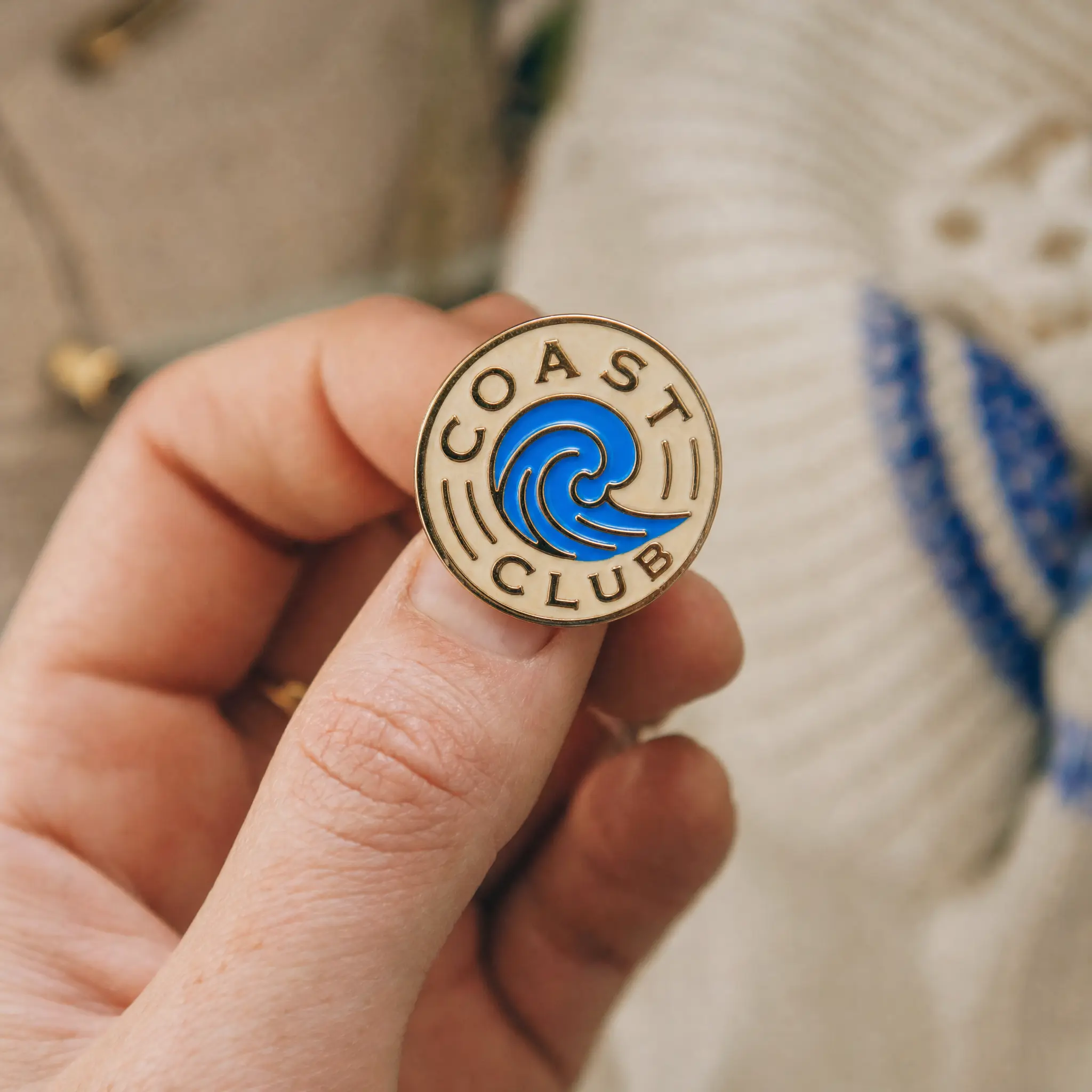 A vintage enamel badge that reads "Coast Club" around an azure wave
