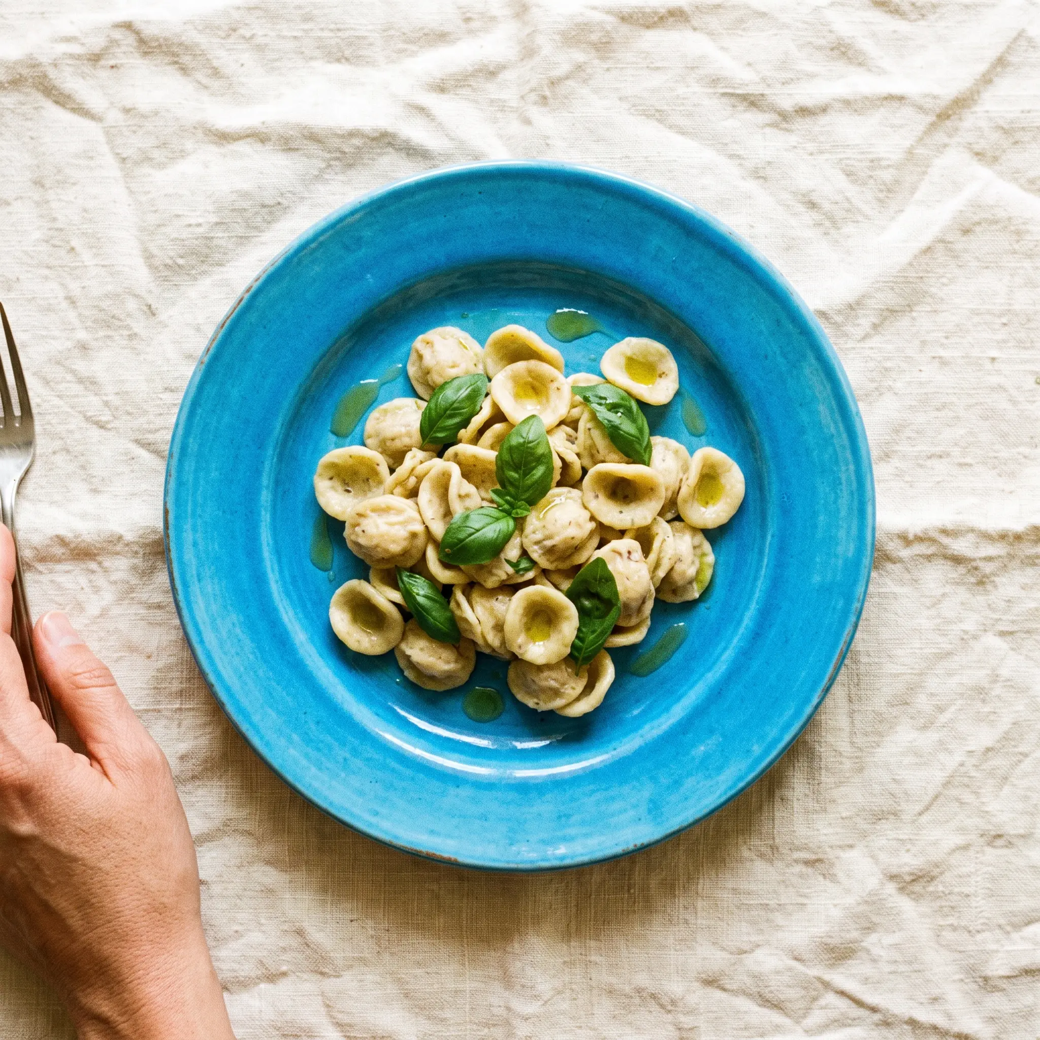 Handmade pasta with basil on an azure ceramic plate