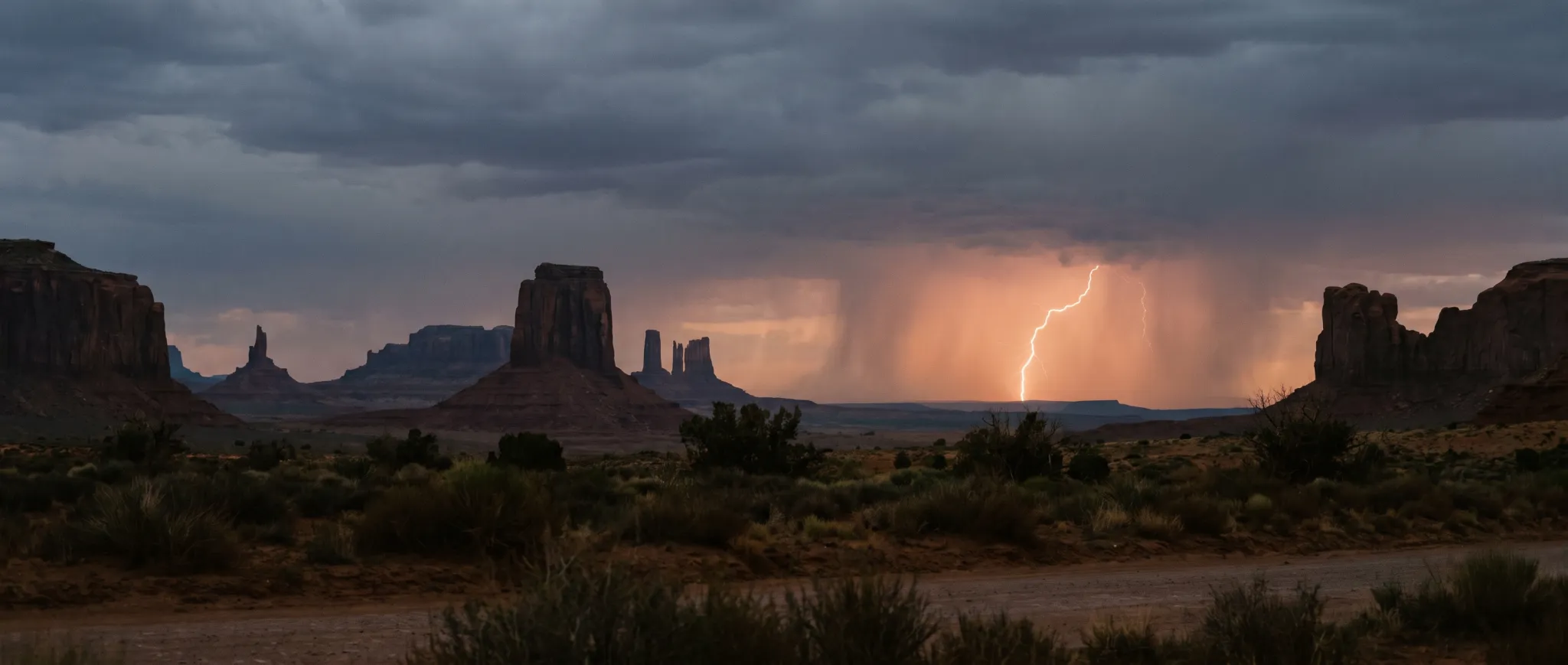 A lightning storm over desert buttes at dusk
