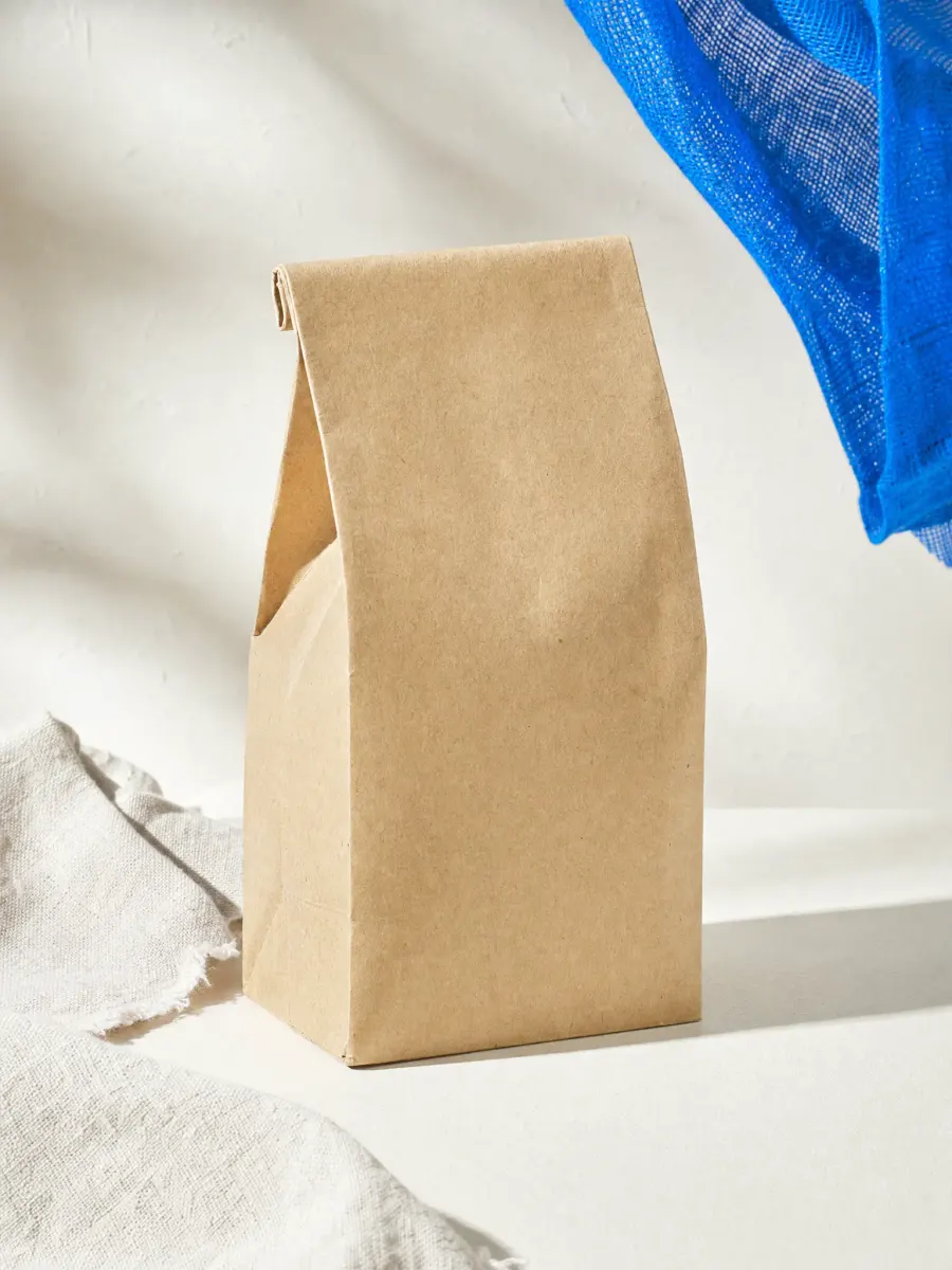 A plain kraft paper coffee bag with no label on a white background