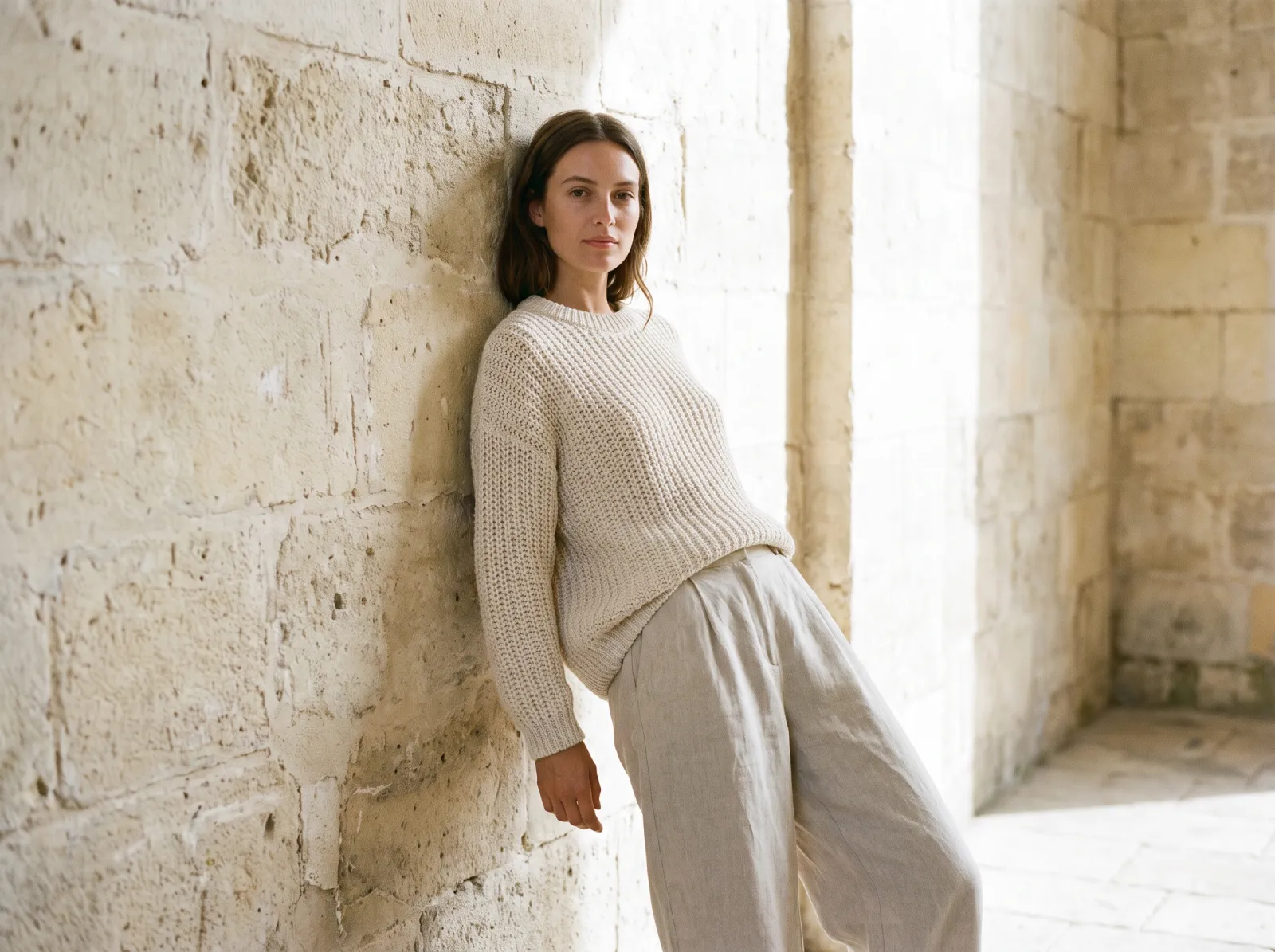 Knitwear on a model against a plain stone wall