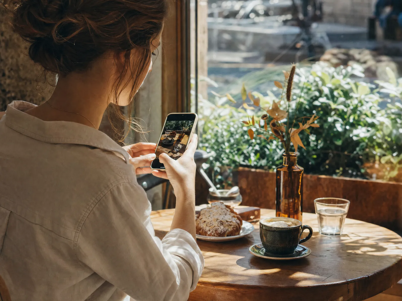 A woman photographing coffee and pastries at a cafe table