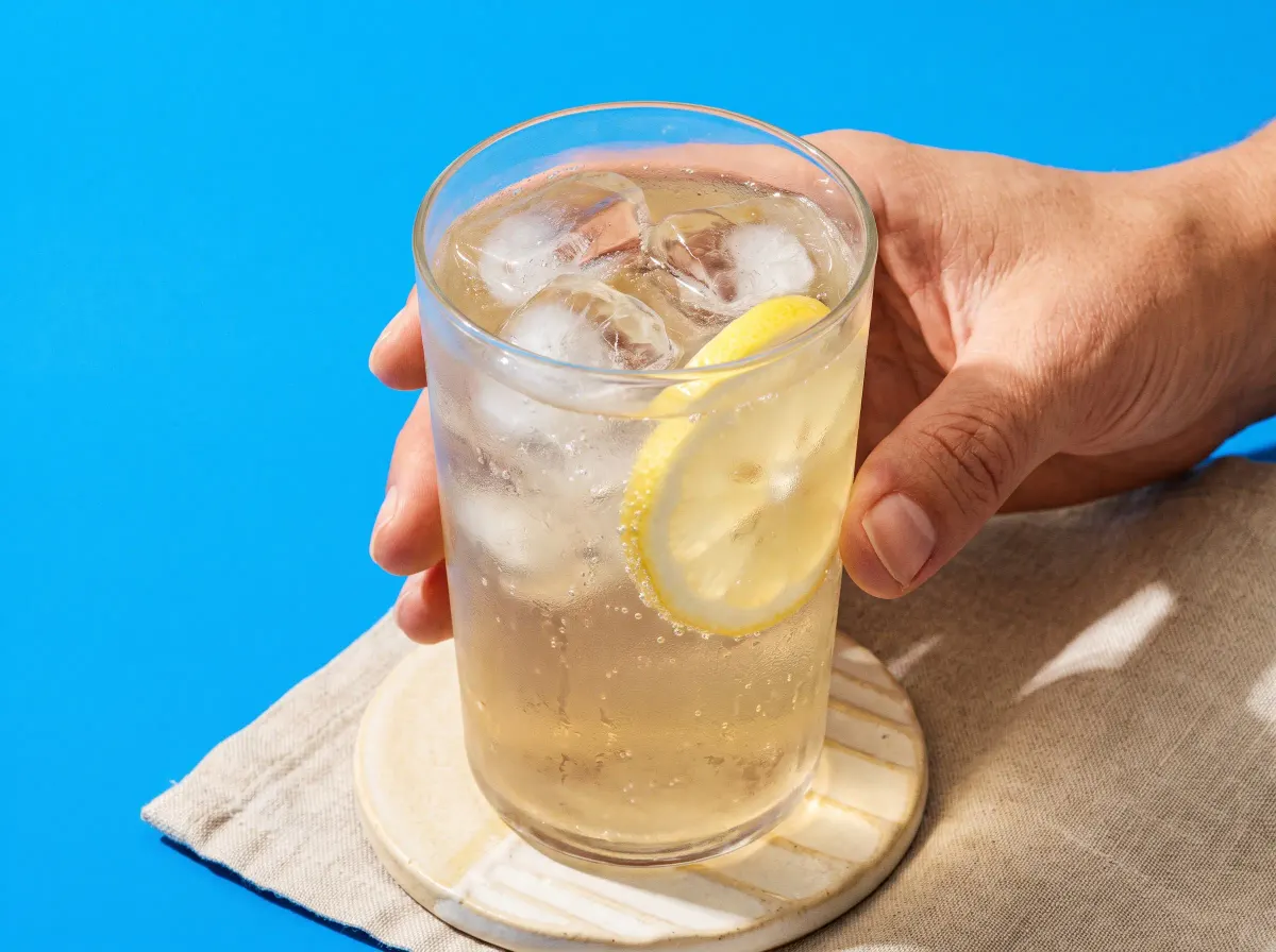A bright summer drink with ice and a lemon slice against an azure background