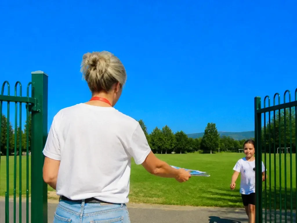 A volunteer handing out flyers at a school gate