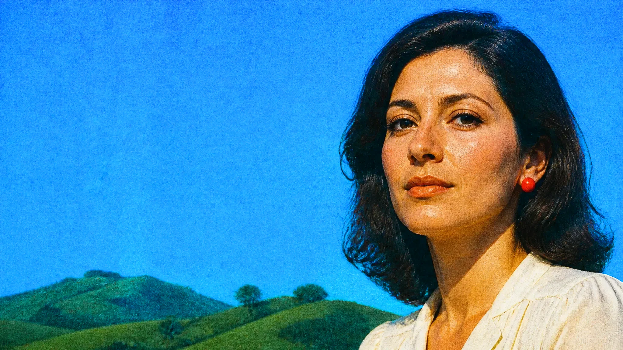 A studio headshot of a woman in a cream blouse against a blue backdrop