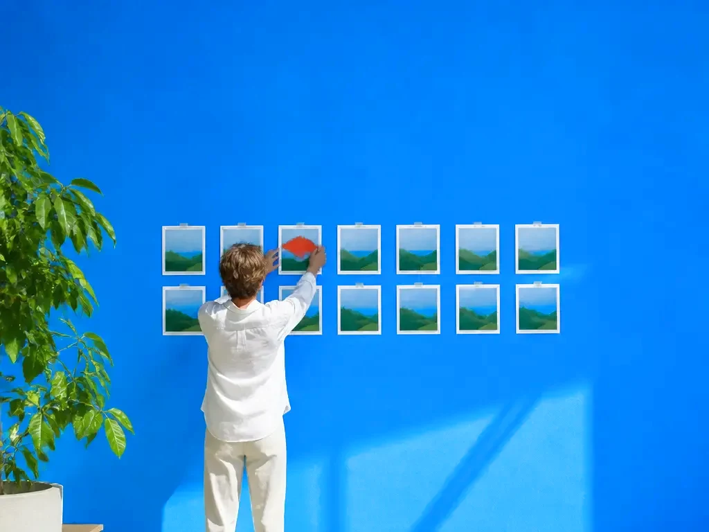 An art director pinning up a grid of prints