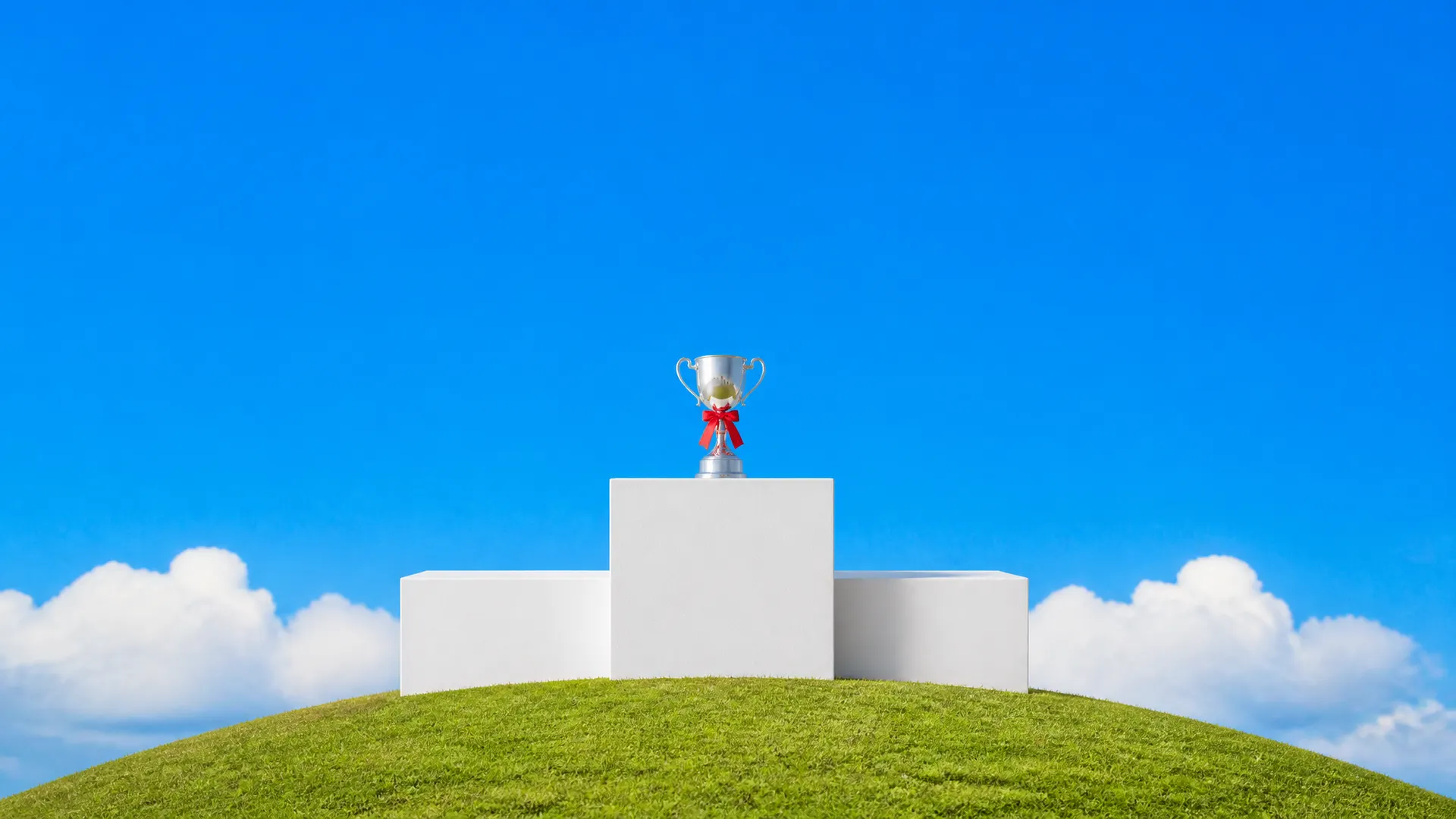 A white three-step winners' podium on a hilltop with a silver trophy tied with an orange ribbon on the top step.