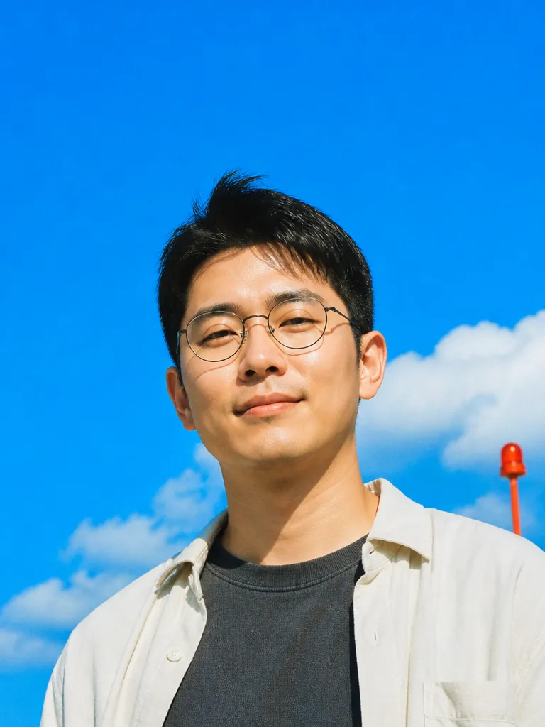 Headshot of a man in round glasses against a blue sky