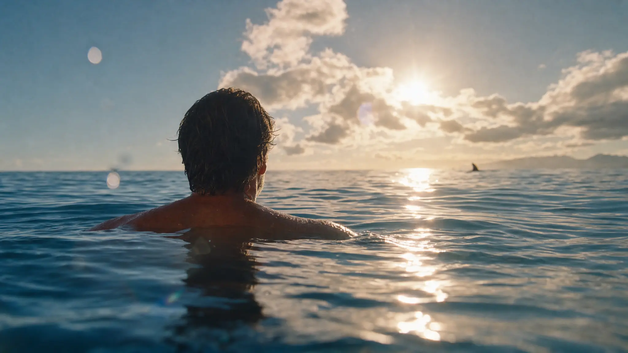 A swimmer looking across an azure sea in warm sunset light