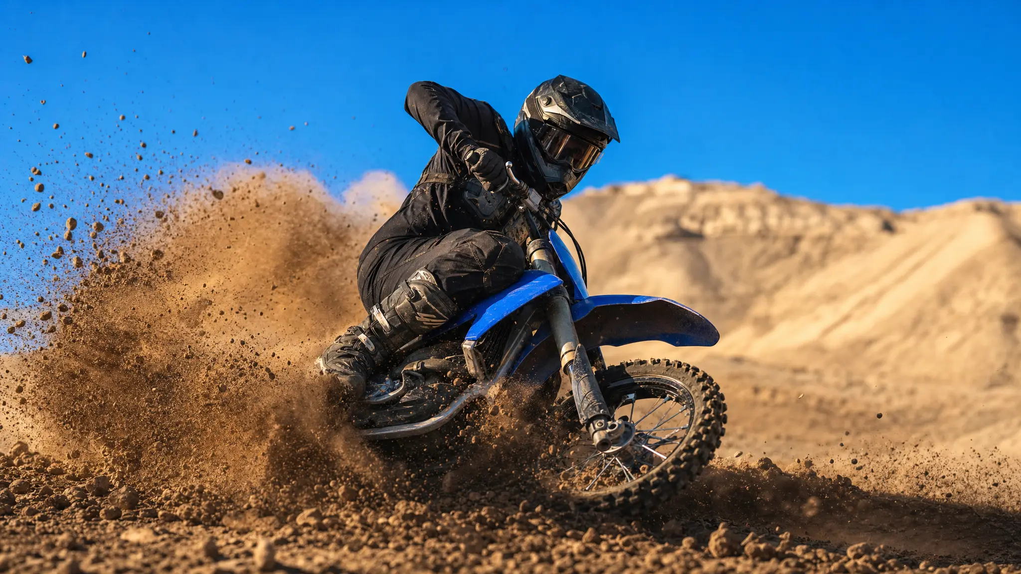A motocross rider turning through a trail of sunlit dirt
