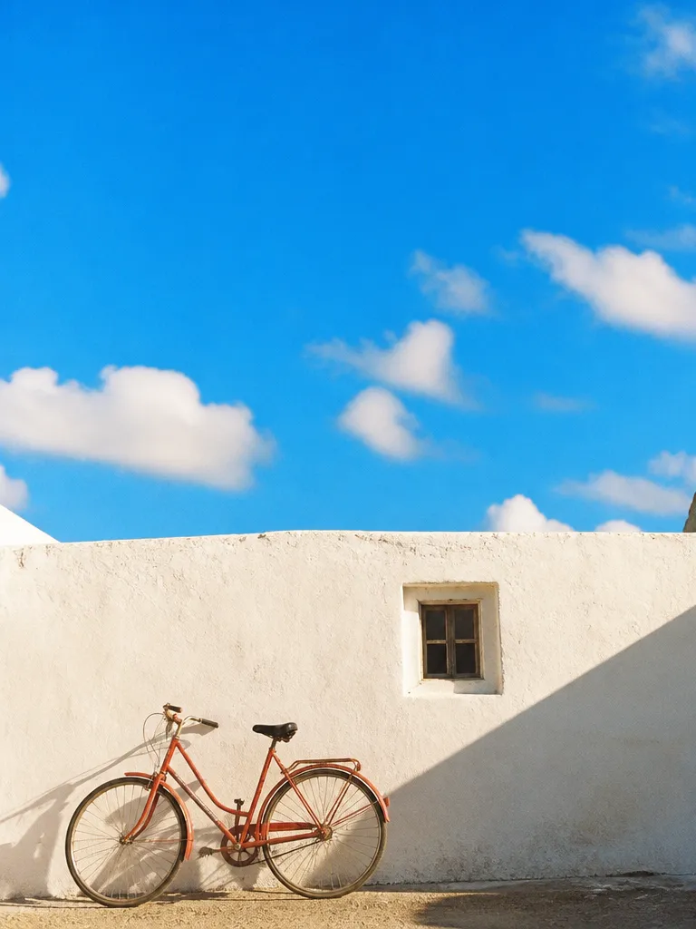 A red bicycle against a white wall in warm light